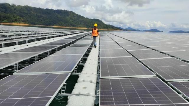 A worker walks among solar panels in a solar farm in Sarawak.